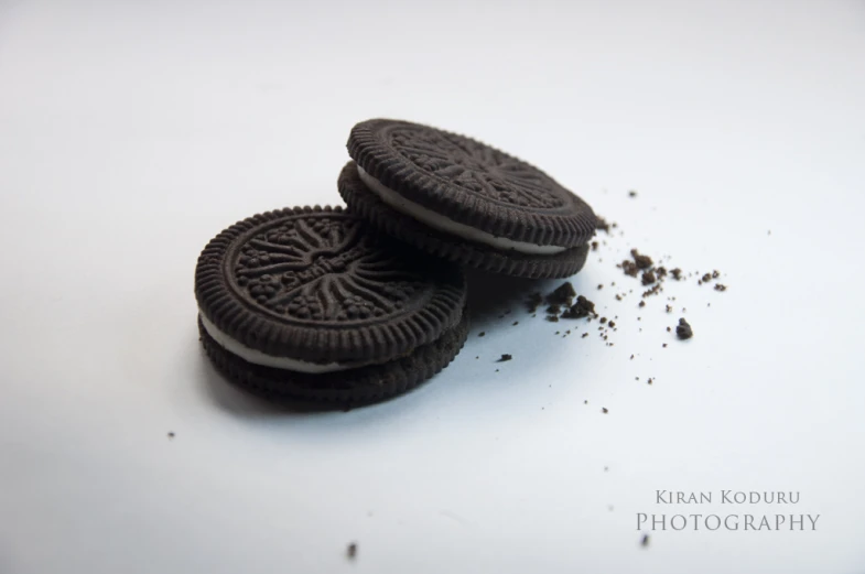 there are two oreo cookies and a broken one on a white surface