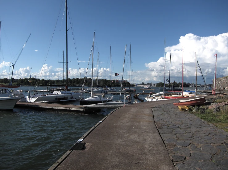 several boats parked next to a concrete wall with flags on it