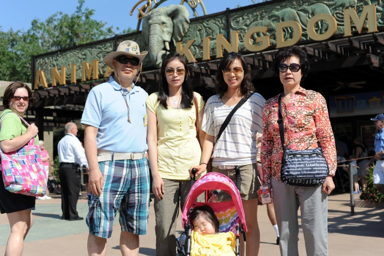 two people and a child stand at an animal kingdom sign