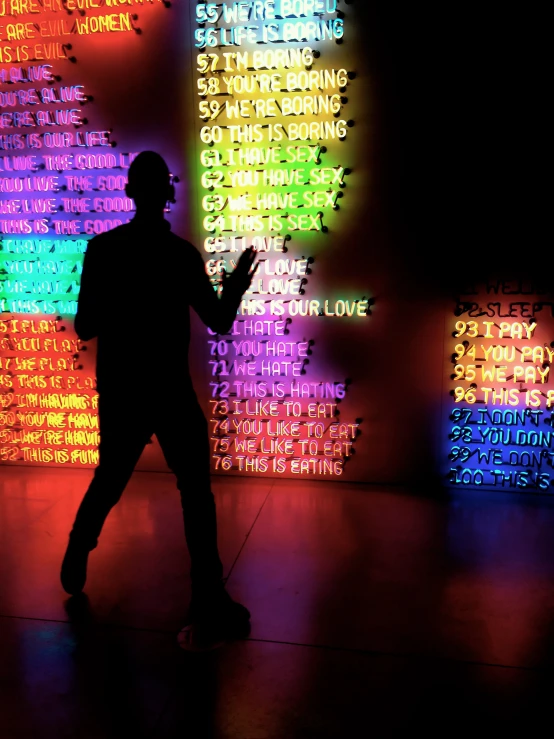 person in front of wall of colorful neon letters