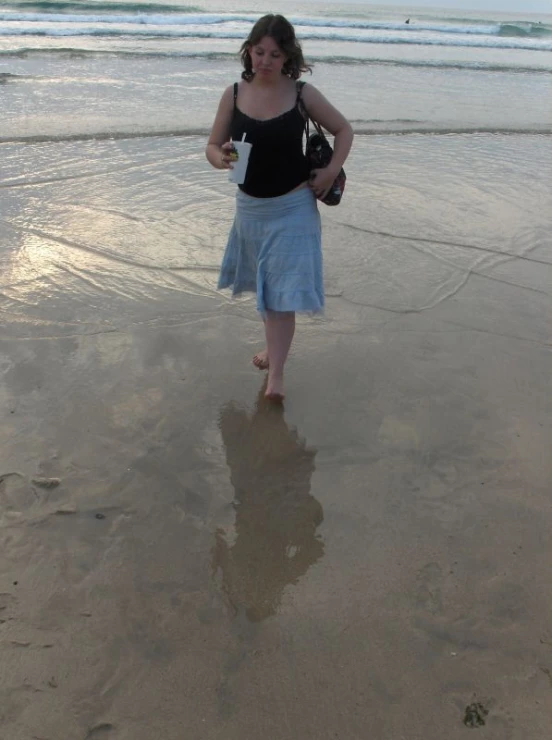 woman in blue skirt walking on beach near ocean