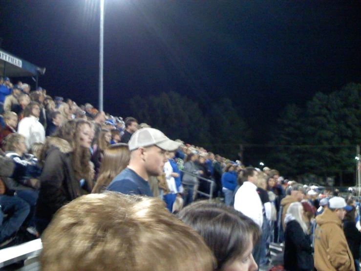 a lot of people standing in front of the stands at a football game