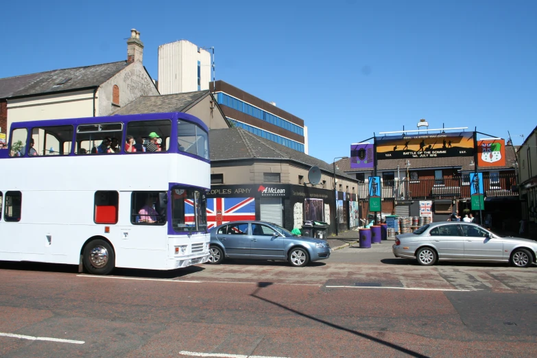 a white double decker bus drives down a street