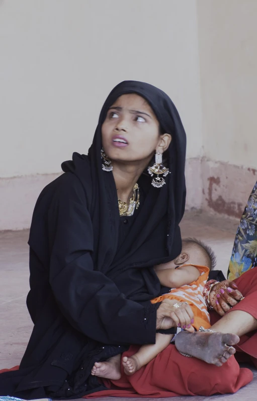 two women with their baby in their arms, look up