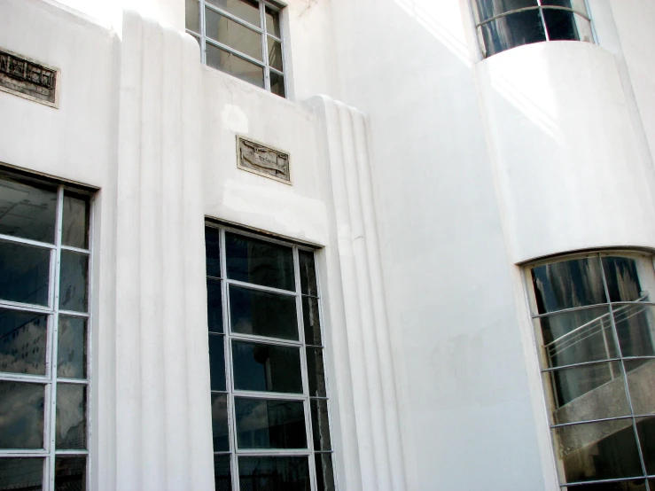 a white building that has a clock at the top and two windows on each side