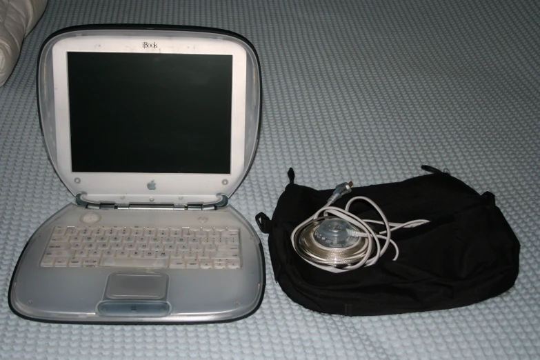 the open laptop is left on the bed beside the purse