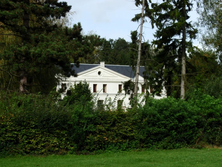 a white house sits near a grassy field and trees