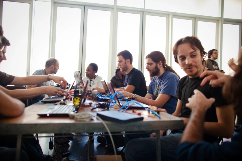 many people sitting around a table working on electronics