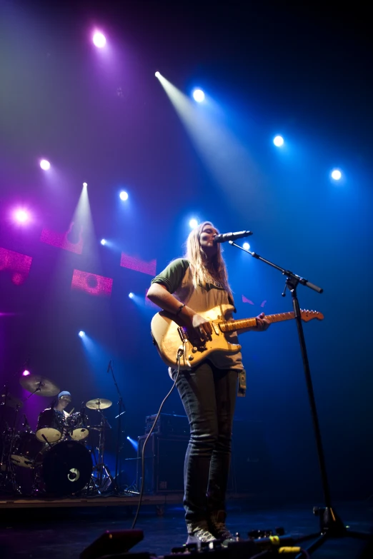 a man is playing a guitar and singing into a microphone on stage