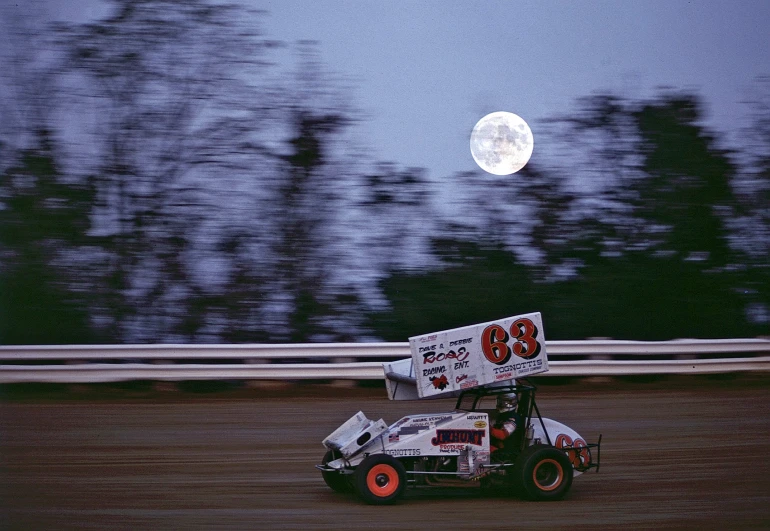 the race car is driving in the dirt track