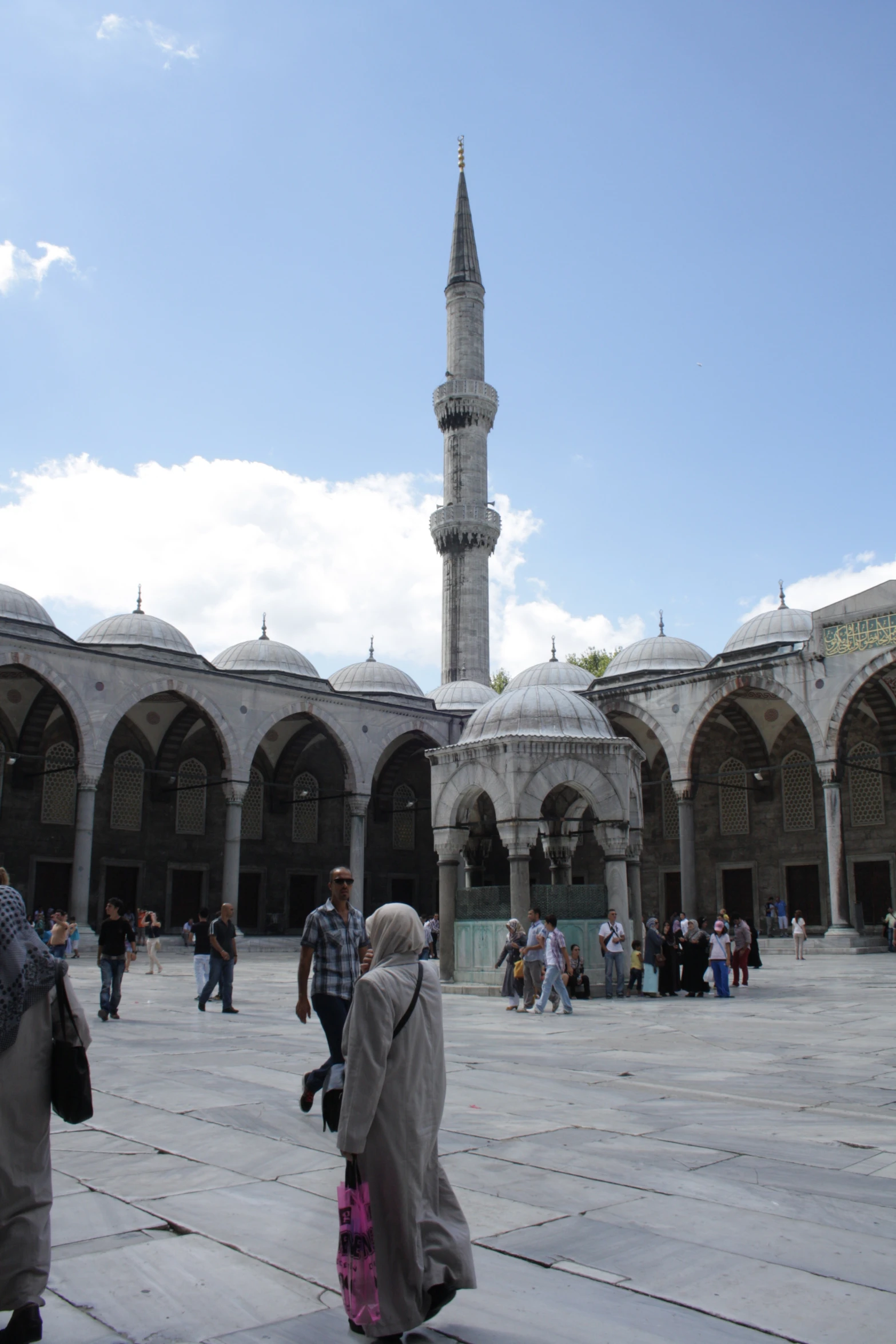 people walk around in a courtyard next to an old mosque