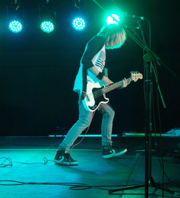 a man with a guitar on stage and four spotlights