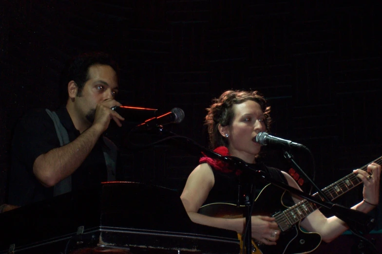 a man and a woman playing guitar on stage