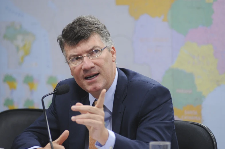 a man with glasses talking while holding a microphone