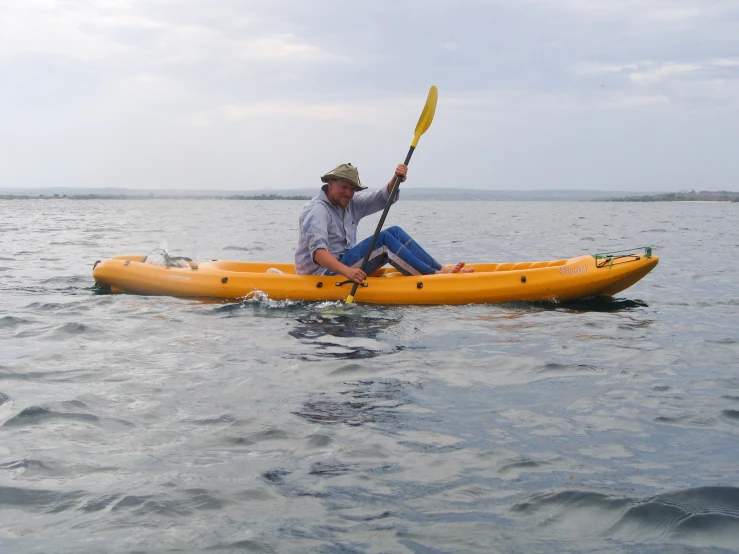 a man wearing a hat is sitting in his yellow kayak