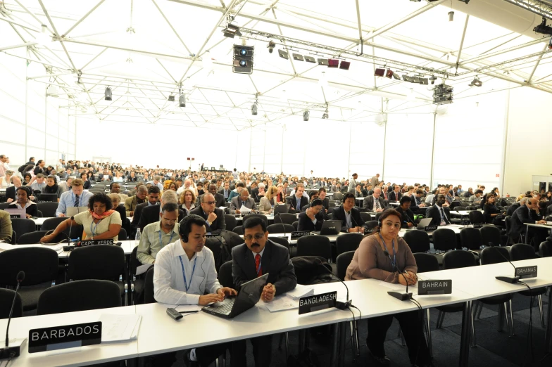 many people are sitting at tables on laptop computers