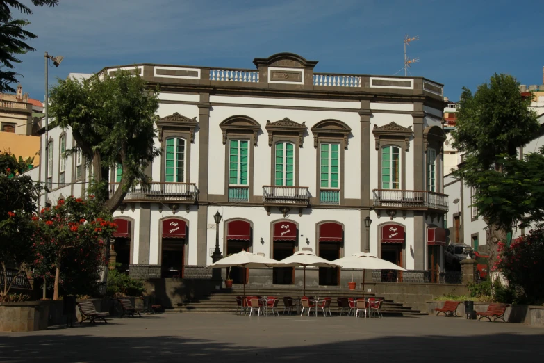 a large house with red chairs under umbrellas