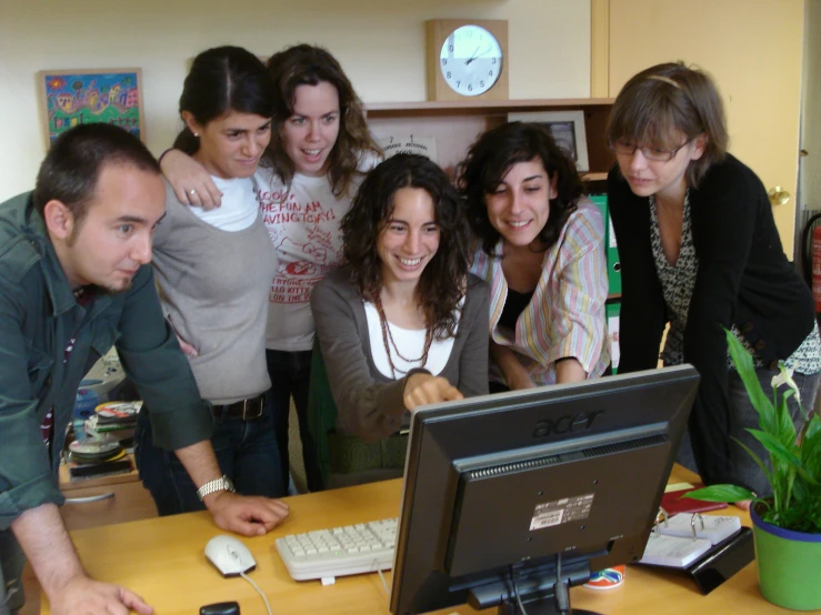 a group of women are gathered around a computer