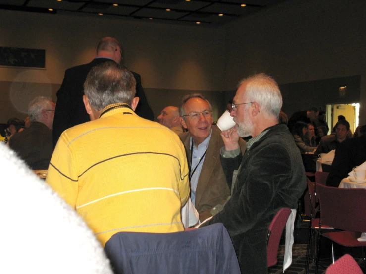 two men in front of others drinking coffee