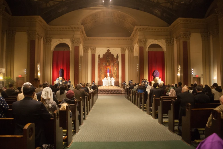 a church filled with people sitting and standing in front of pews