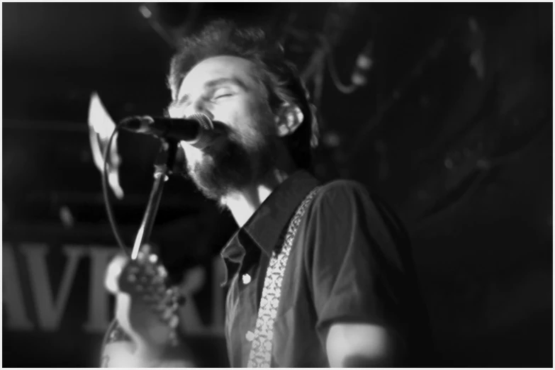 a man holding an acoustic guitar and singing into a microphone