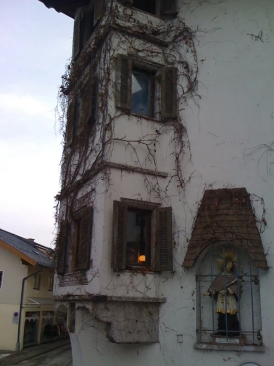 the clock is near a white building with vines growing on it
