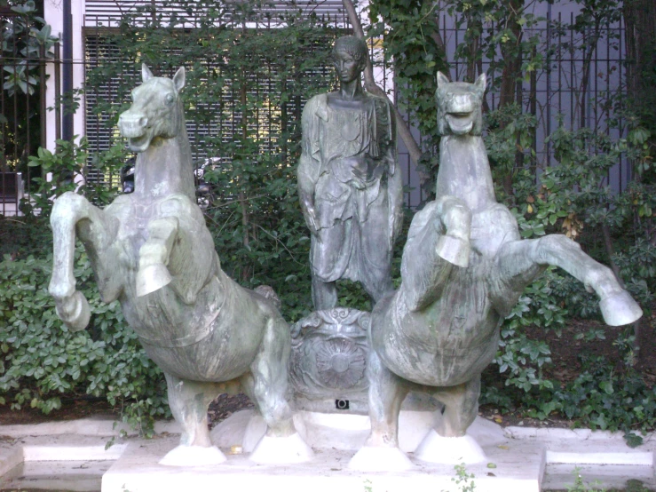 statue of three horses in front of a building
