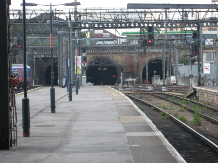 a train station with many tracks, with train and signals above