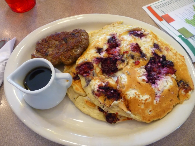 breakfast set on table including pancakes, bacon and juice