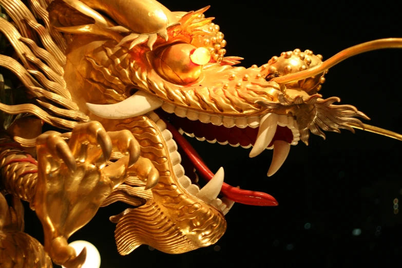 a gold dragon statue sitting in the middle of a black background