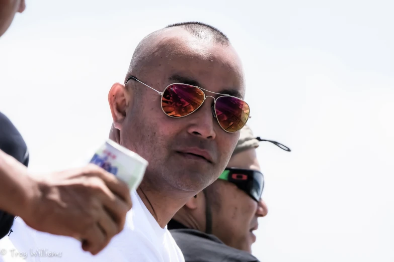 an old man with red sunglasses standing next to another