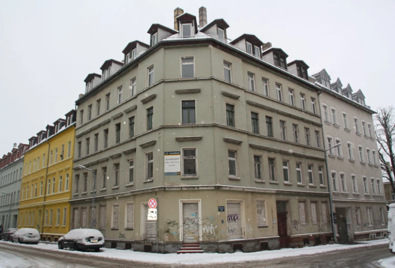 there is a very old building that has cars parked on the side of the street