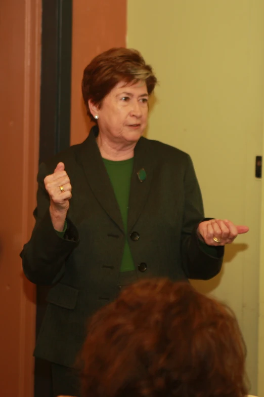 a woman in a green blazer is making a presentation