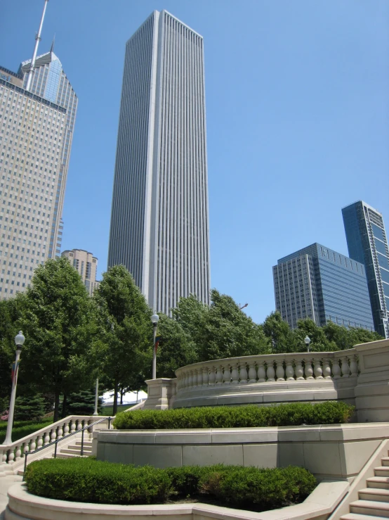 a park area with several steps, bushes, and tall buildings