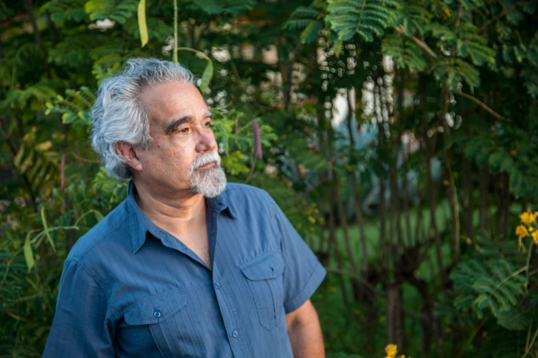 an older man wearing a blue shirt in the grass