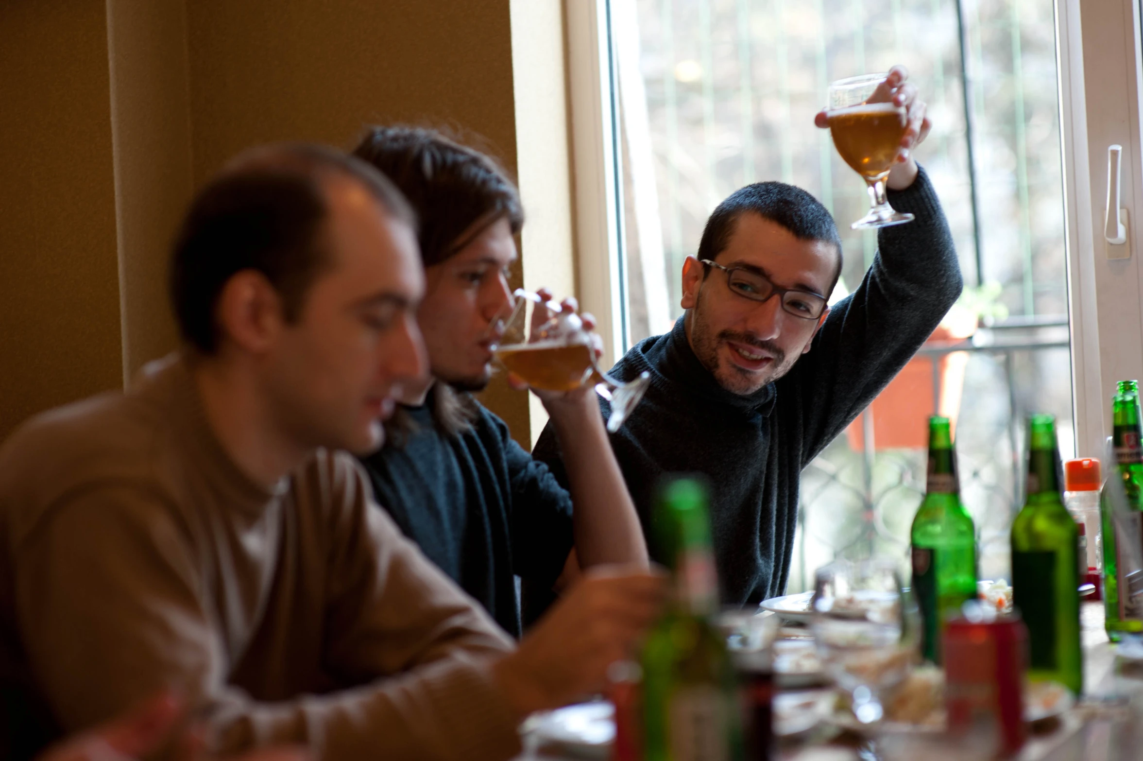 two men in brown jackets drinking wine and some bottles