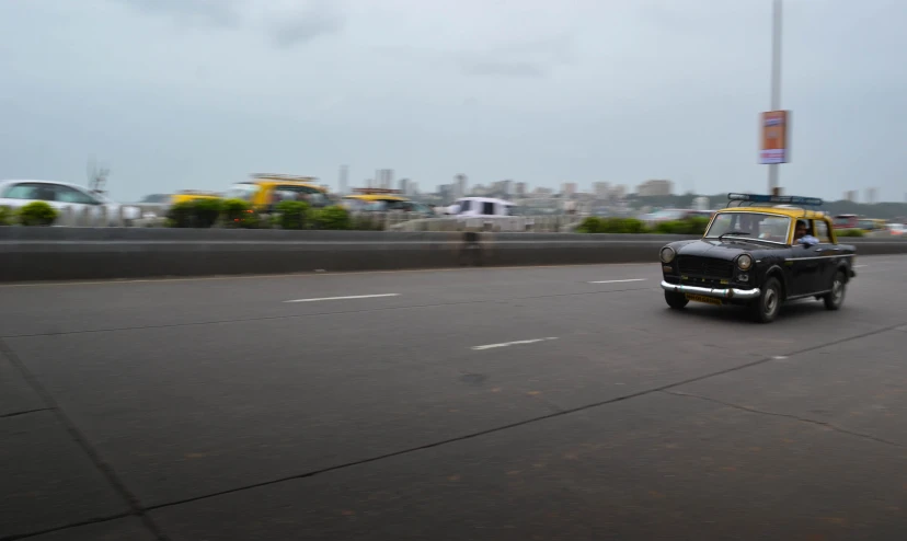 a car drives down an urban highway, with a skyline in the background