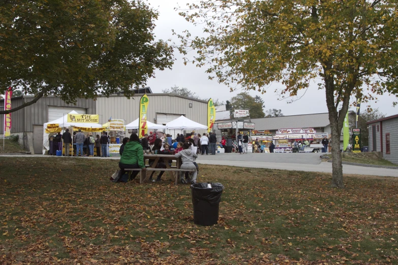 several people sit at a picnic table in an open area