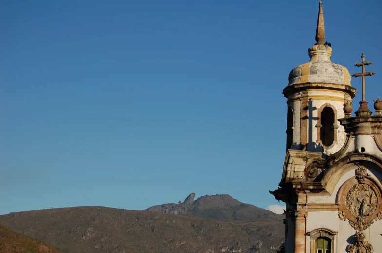 a tall tower with a clock near a mountain range
