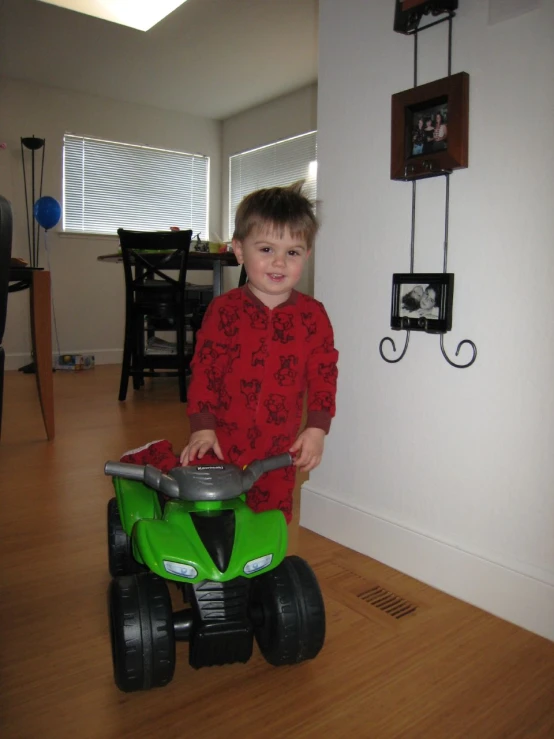 a small boy rides a toy tractor near the wall