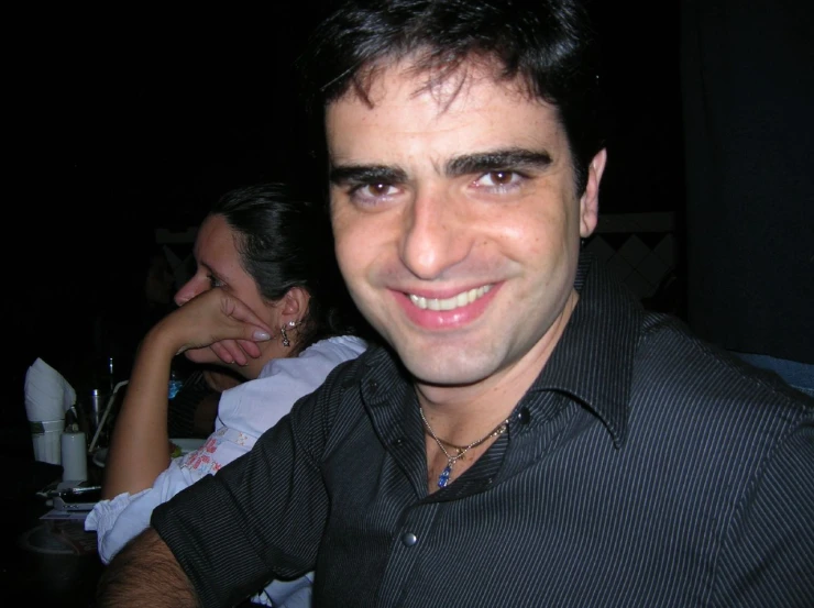a smiling man sitting in front of people