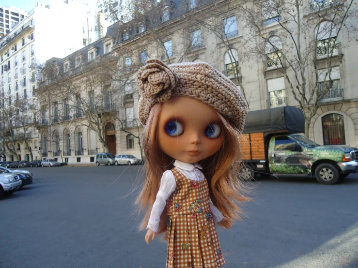 a doll standing on a street corner next to buildings