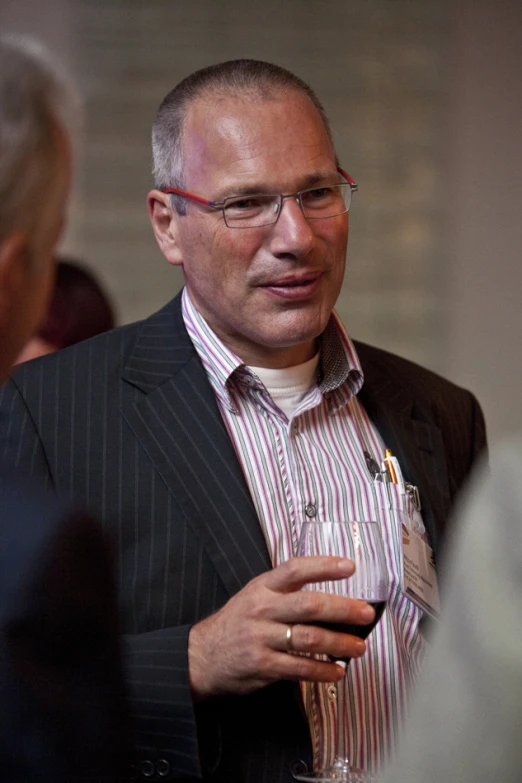 a man in suit jacket and striped shirt drinking some beverage