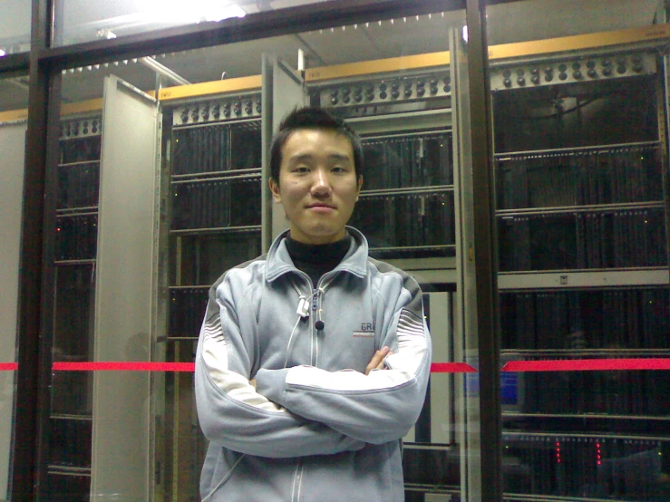 a young man stands in front of an server rack