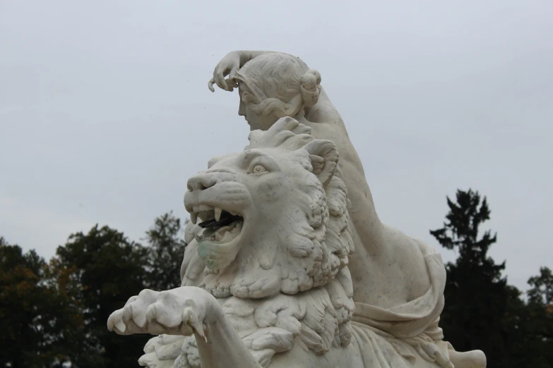 a lion statue sitting in front of a forest