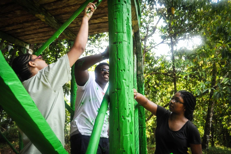 some people hanging up a green pole