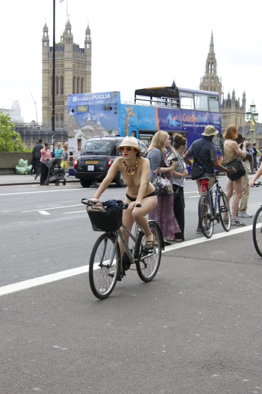 three people on bicycles on the road with other people on side of street