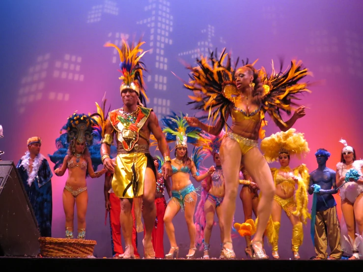 a group of dancers with some wearing orange dresses and standing on stage