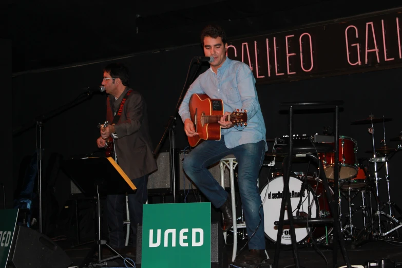 two people on stage playing guitars and singing