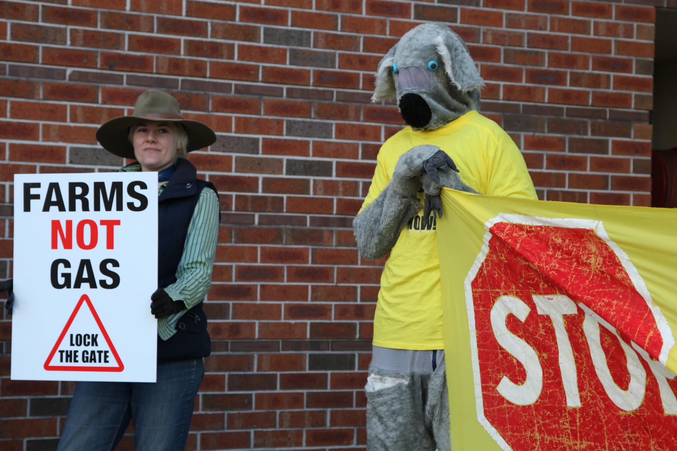 a couple of people standing in front of a brick building holding signs